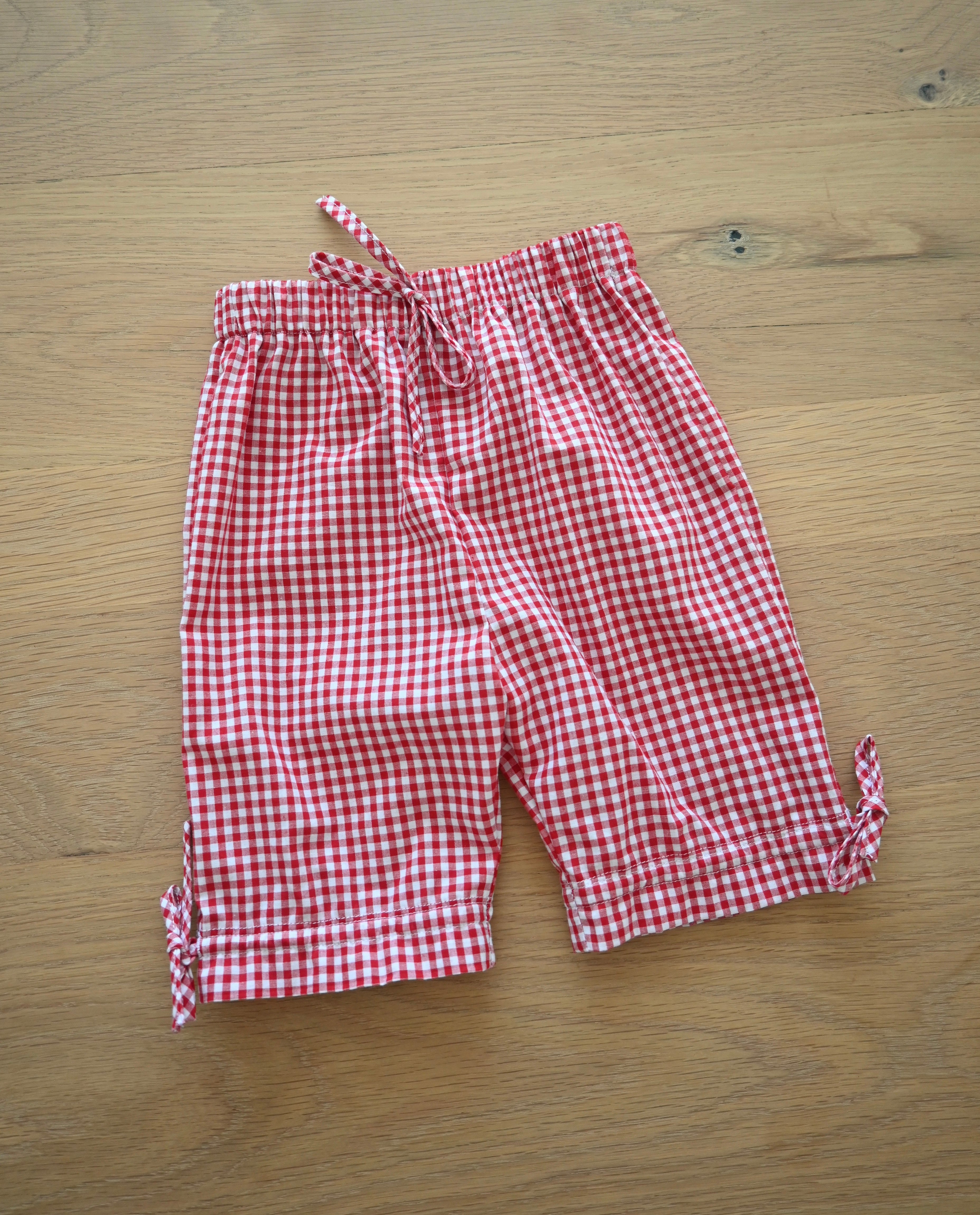 Red and white gingham pants on a wooden surface